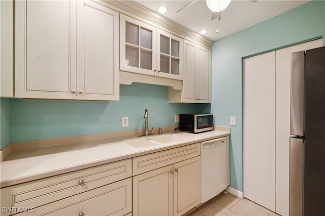 kitchen featuring a sink, freestanding refrigerator, light tile patterned flooring, dishwasher, and light countertops