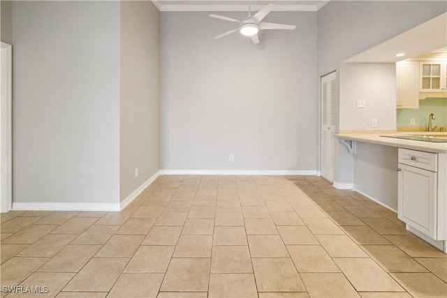 kitchen with white cabinetry, ornamental molding, light countertops, and ceiling fan