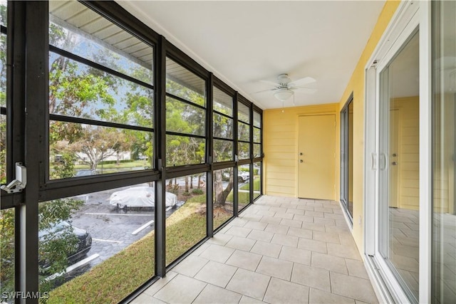 unfurnished sunroom featuring a ceiling fan and a wealth of natural light