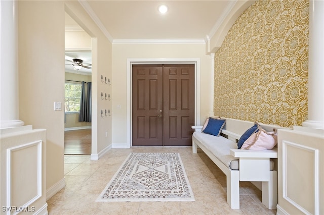 foyer entrance featuring crown molding, ceiling fan, tile patterned floors, and baseboards