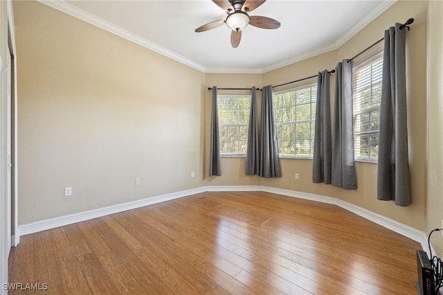 unfurnished room with healthy amount of natural light, a ceiling fan, hardwood / wood-style flooring, baseboards, and ornamental molding