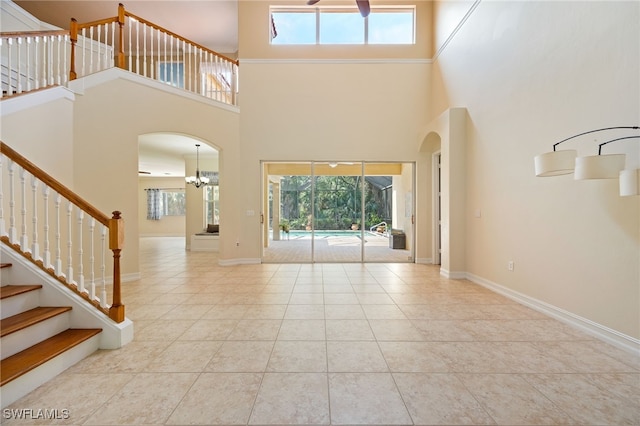 tiled foyer entrance with a towering ceiling, healthy amount of natural light, arched walkways, and stairs