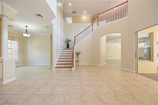 stairs with ornate columns, ornamental molding, arched walkways, baseboards, and tile patterned floors