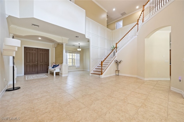 foyer entrance with arched walkways, stairway, ornamental molding, decorative columns, and tile patterned floors