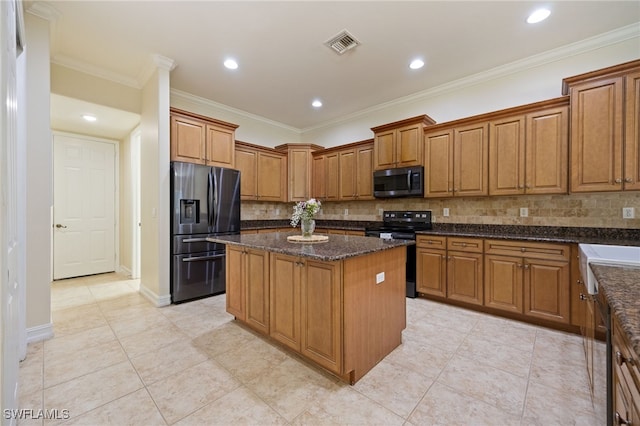 kitchen with refrigerator with ice dispenser, black electric range, stainless steel microwave, a kitchen island, and brown cabinetry