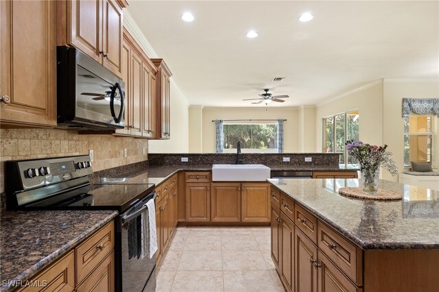 kitchen with appliances with stainless steel finishes, a sink, ceiling fan, brown cabinets, and ornamental molding