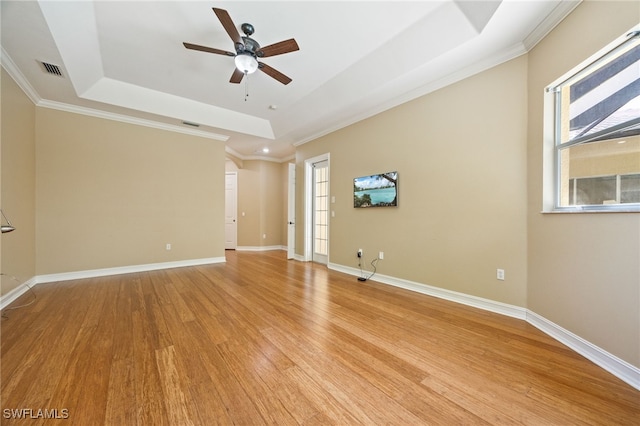 spare room with a raised ceiling, a ceiling fan, light wood-style floors, healthy amount of natural light, and crown molding