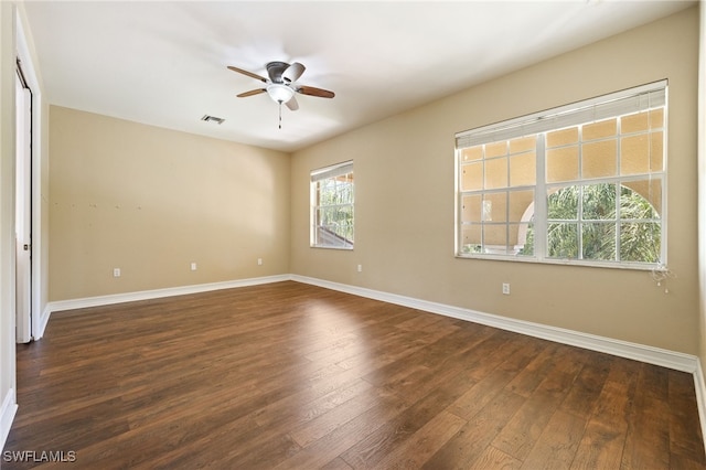 spare room featuring a ceiling fan, dark wood-type flooring, and baseboards