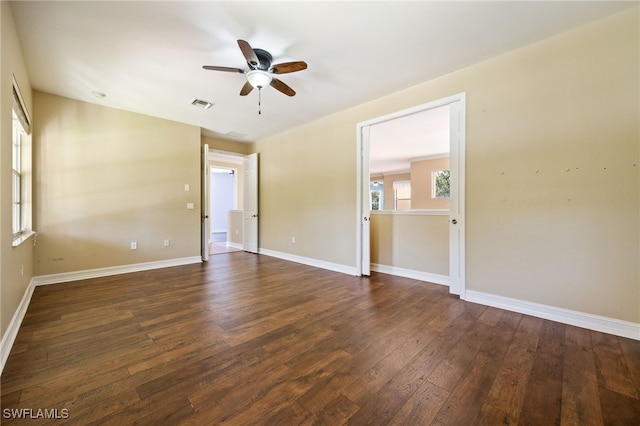 unfurnished room with dark wood-style flooring, a ceiling fan, and baseboards