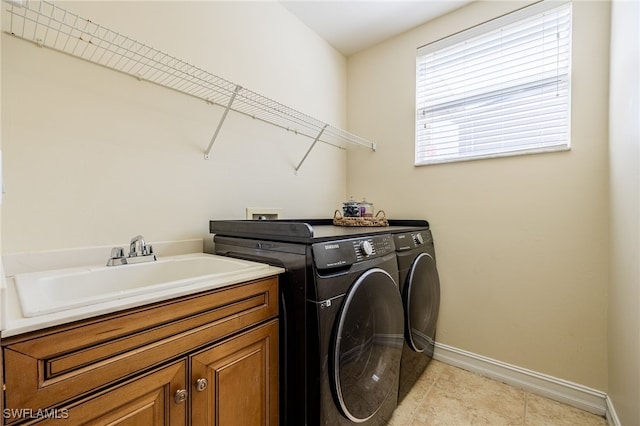laundry area with washing machine and dryer, baseboards, cabinet space, and light tile patterned flooring