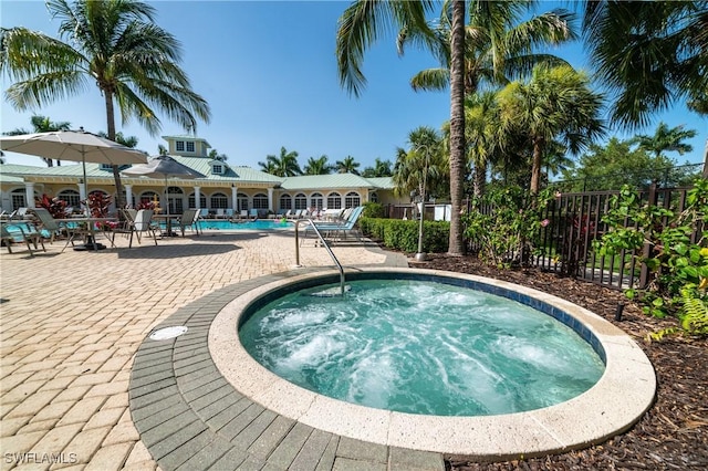 community pool featuring a hot tub, fence, and a patio