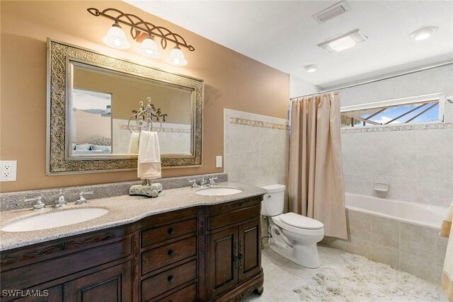 bathroom with toilet, tile patterned floors, double vanity, and tiled shower / bath combo