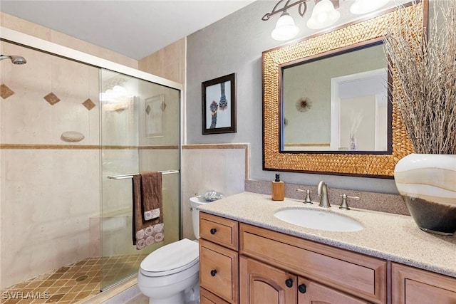full bath with toilet, a stall shower, tile walls, and vanity