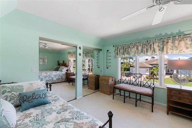 carpeted bedroom featuring multiple closets and ceiling fan