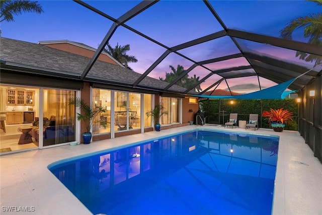 pool at dusk featuring a patio and a lanai