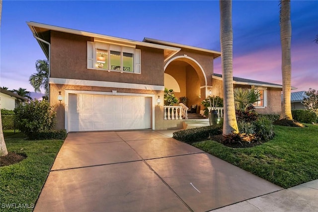 view of front facade with an attached garage, stucco siding, concrete driveway, and a lawn