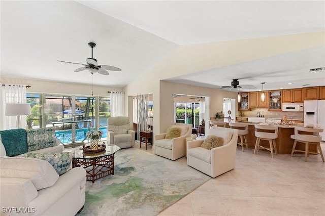 living area with ceiling fan, light tile patterned floors, and lofted ceiling