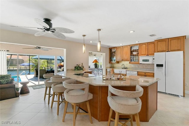 kitchen featuring white appliances, brown cabinetry, glass insert cabinets, a kitchen breakfast bar, and recessed lighting