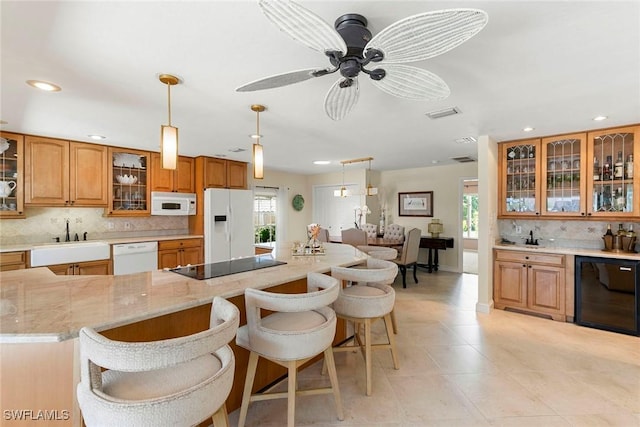 kitchen featuring white appliances, recessed lighting, a sink, tasteful backsplash, and a breakfast bar