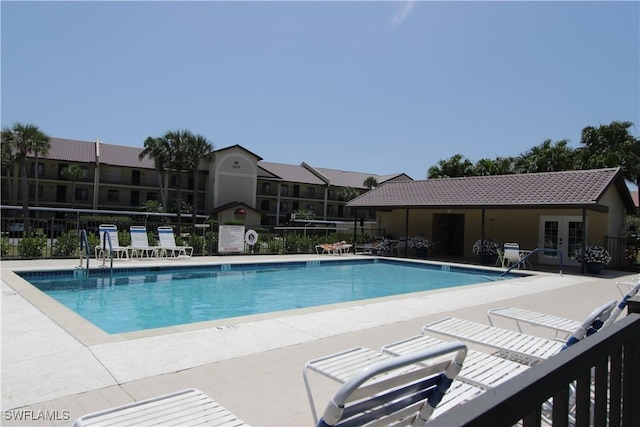 community pool with french doors, fence, and a patio