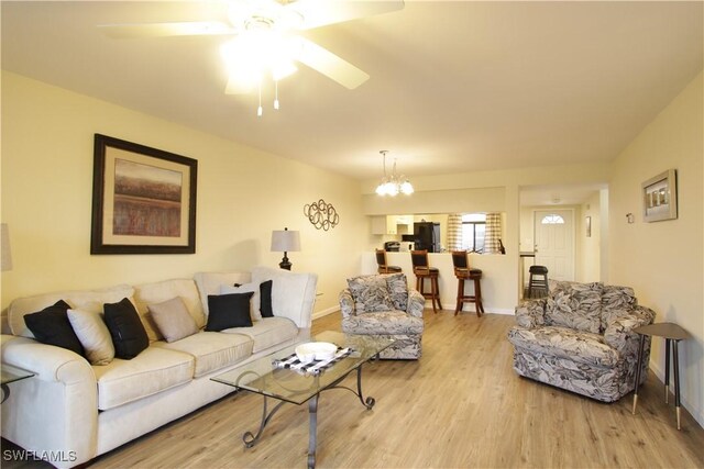 living room featuring wood finished floors, a chandelier, a ceiling fan, and baseboards