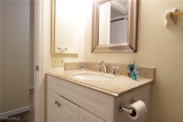 bathroom featuring vanity, baseboards, and wood finished floors