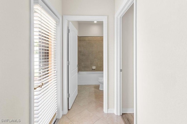 corridor featuring light tile patterned floors and baseboards