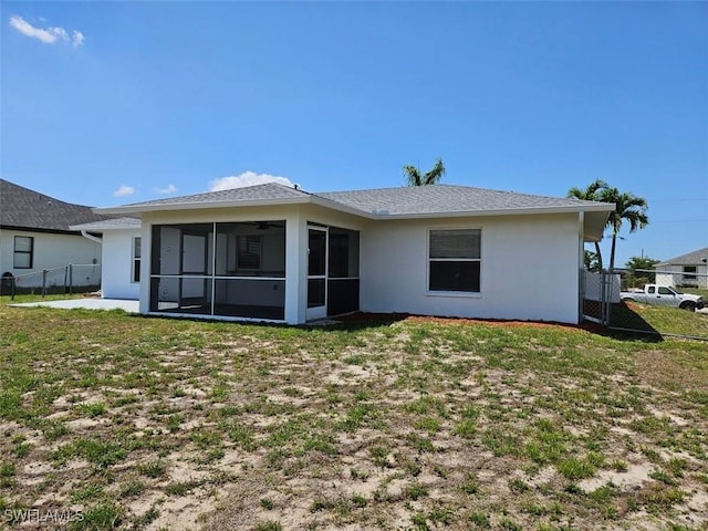 417 NW 18th Pl, Cape Coral, FL 33993 - rear view of house with a sunroom, stucco siding, fence, and a lawn