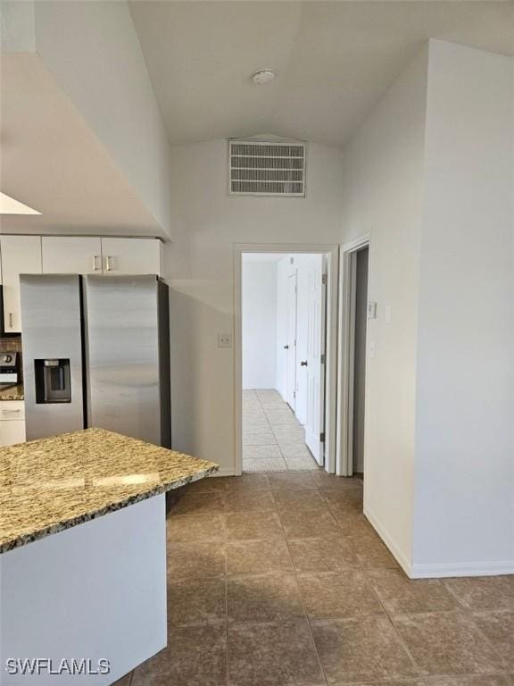 417 NW 18th Pl, Cape Coral, FL 33993 - kitchen with high vaulted ceiling, visible vents, white cabinets, light stone countertops, and stainless steel fridge with ice dispenser