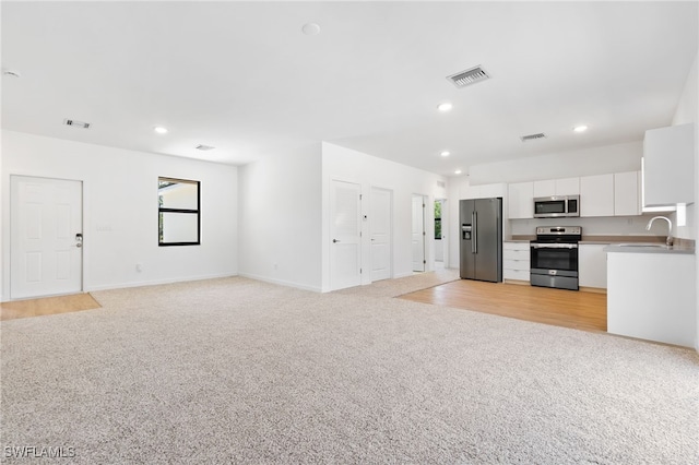 713 Wells Ave, Lehigh Acres, FL 33972 - unfurnished living room with a sink, light carpet, visible vents, and recessed lighting