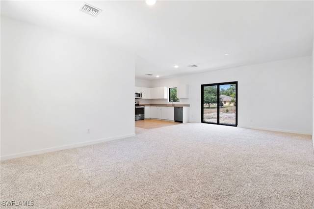 713 Wells Ave, Lehigh Acres, FL 33972 - unfurnished living room with baseboards, light carpet, and recessed lighting