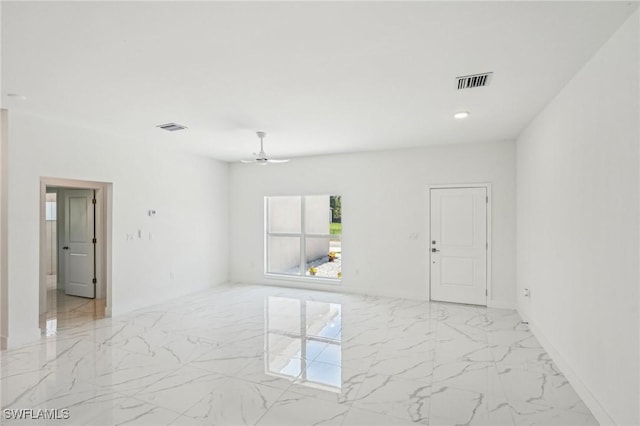 empty room featuring light marble finish floors and ceiling fan