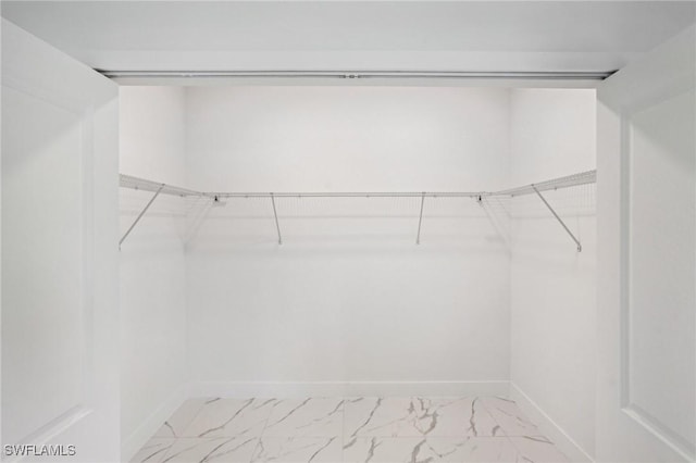 walk in closet featuring light marble finish flooring