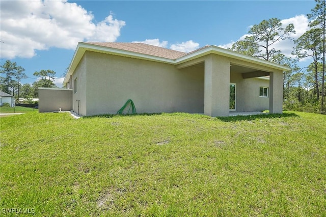view of side of home featuring stucco siding and a yard