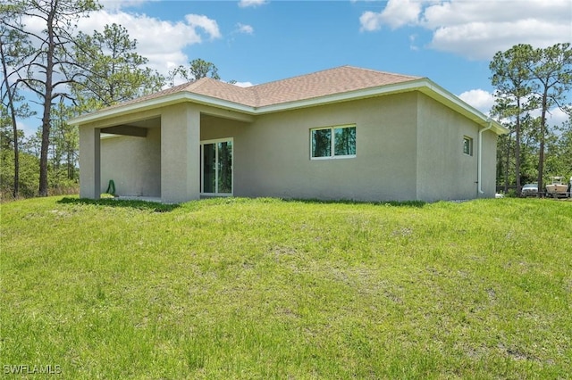 rear view of house with stucco siding and a lawn