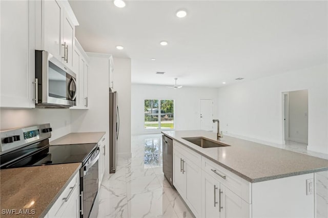 kitchen with appliances with stainless steel finishes, a sink, light marble finish floors, white cabinetry, and recessed lighting