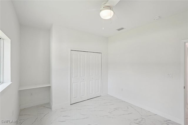 unfurnished bedroom with marble finish flooring, baseboards, a closet, and ceiling fan
