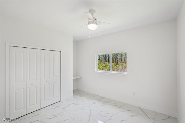 unfurnished bedroom with marble finish floors, a closet, and ceiling fan