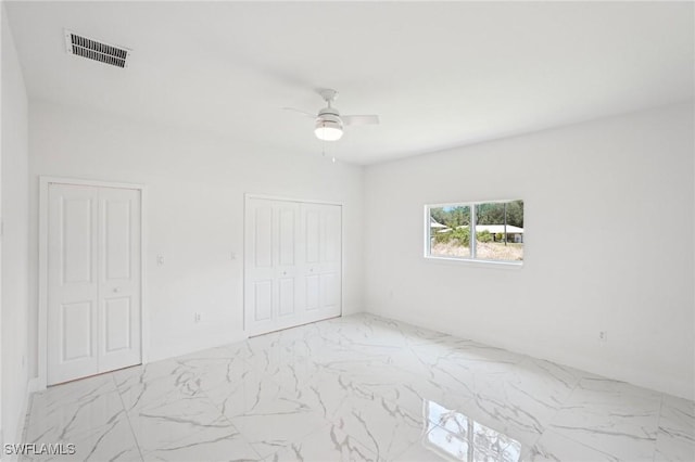 unfurnished bedroom with marble look tile flooring and a ceiling fan