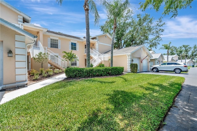 view of side of property with stairway, a yard, stucco siding, and a garage