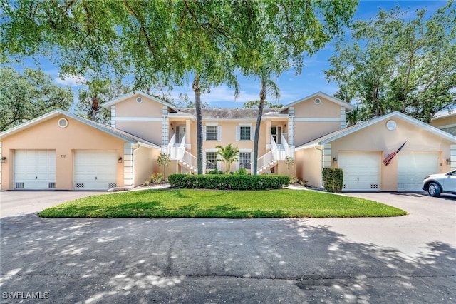 view of front of property featuring stucco siding, a front yard, stairway, and a garage