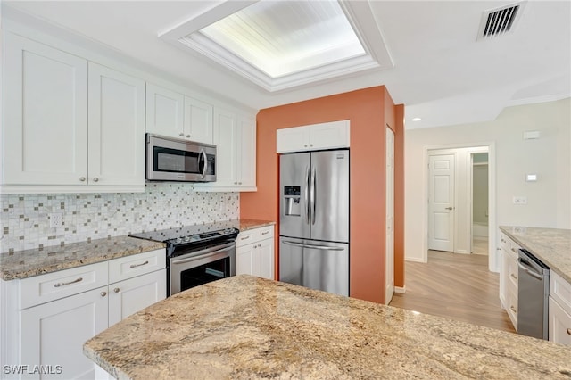 kitchen featuring stainless steel appliances, white cabinetry, tasteful backsplash, light wood-style floors, and recessed lighting