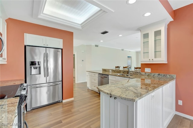 kitchen with appliances with stainless steel finishes, a sink, light wood-type flooring, baseboards, and white cabinets