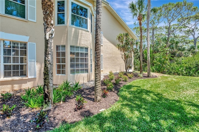 view of side of property featuring stucco siding and a lawn