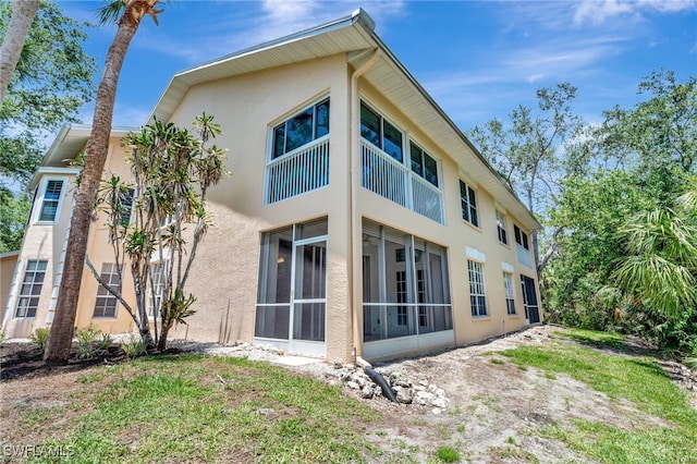 back of property featuring stucco siding and a sunroom