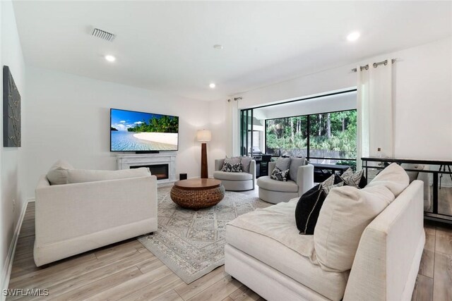 10427 Ventana Ln, Naples, FL 34120 - living room with light wood-style floors, recessed lighting, and a warm lit fireplace