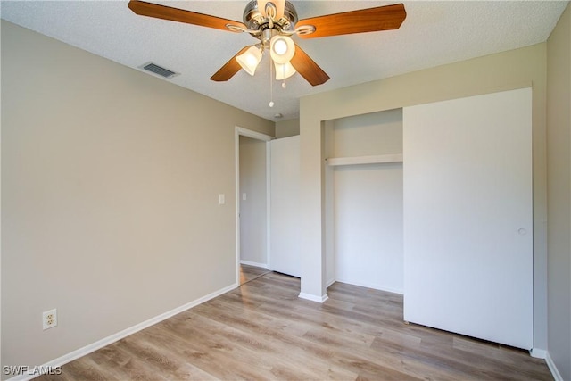 unfurnished bedroom featuring wood finished floors, a closet, a ceiling fan, and baseboards