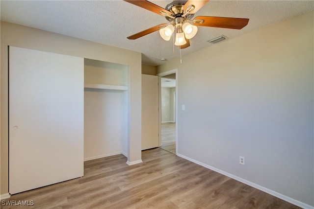 unfurnished bedroom featuring wood finished floors, a closet, baseboards, a textured ceiling, and a ceiling fan