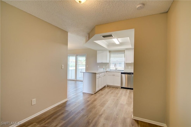 kitchen with stainless steel dishwasher, white cabinetry, light wood-style floors, baseboards, and a textured ceiling