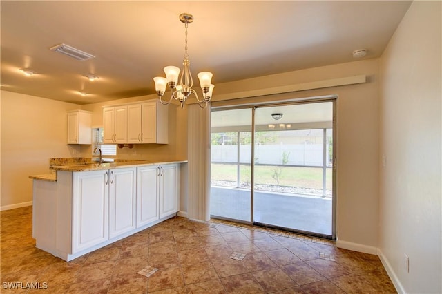 kitchen featuring a chandelier, baseboards, white cabinets, hanging light fixtures, and a peninsula